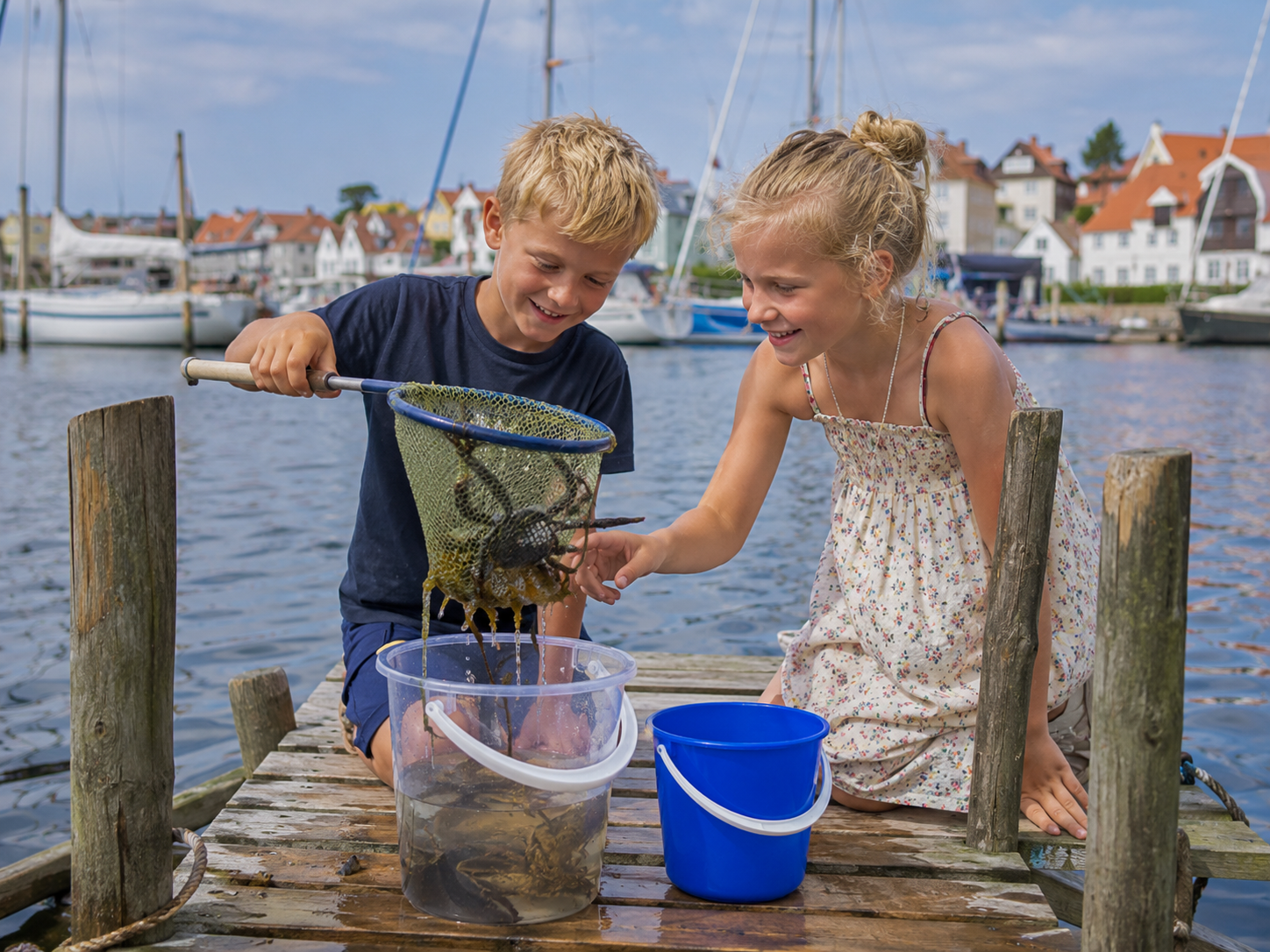To børn fanger krabber fra en bro i en dansk lystbådehavn
